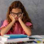 Schülerin sitzt frustriert am Tisch und kommt beim Lernen nicht weiter